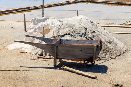 Vintage wooden wheelbarrow near a salt heap at salt farmの写真素材