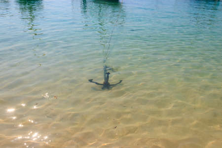 Small boat anchor on a shore of oceanの写真素材