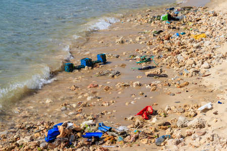 Garbage on a bank of ocean. Pollution of sea, ocean water with waste, plastics garbage. Concept of pollution of ocean, sea and river coastline with plastic trashの写真素材