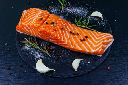Raw salmon fillet with spices on black slateの写真素材