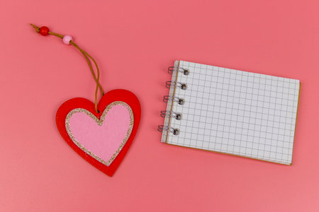 Heart and blank notepad on pastel pink background. Top view, flat lay. Valentine day concept