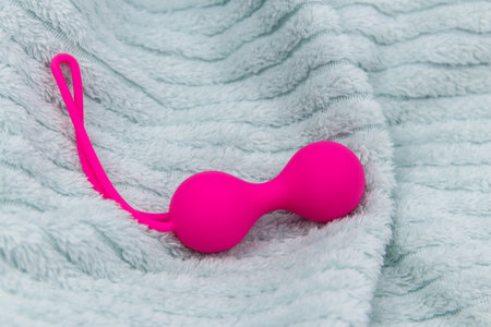 Ben Wa balls or Geisha balls on a soft bedspread. Pink double vaginal balls