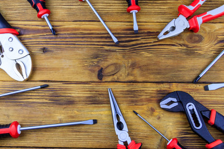 Set of different pliers and screwdrivers on wooden background. top view, copy space