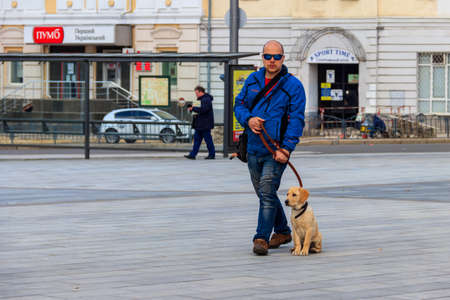 Kharkov, Ukraine - April 5, 2021: Young man with labrador puppy walking on Constitution Square in Kharkiv, Ukraineのeditorial素材