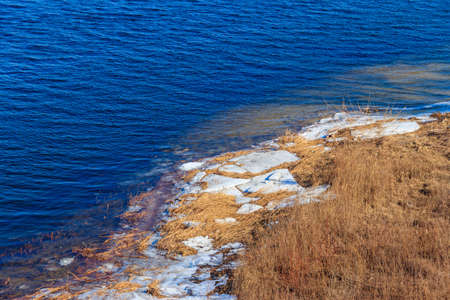 Bank of a wide river with pieces of ice during an ice driftの写真素材