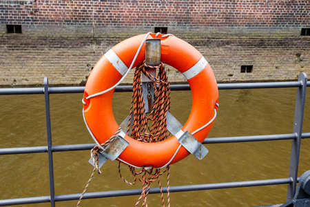 Orange lifebuoy on a berth fence by a riverの写真素材