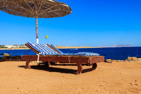 Sun umbrellas and chaise lounges on tropical beach. Concept of rest, relaxation, holidays, resortの写真素材