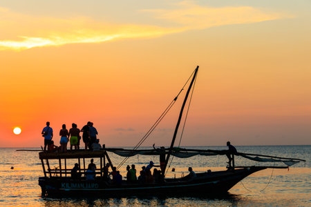Zanzibar, Tanzania - September 16, 2021: Traditional wooden dhow boat with tourists sailing in the Indian ocean during sunset cruise on Zanzibar, Tanzaniaの写真素材