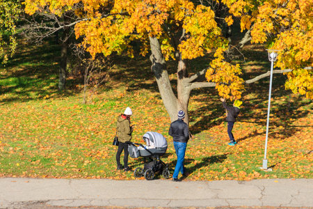 Family with baby carriage walking in autumn park in Kremenchuk, Ukraineの写真素材