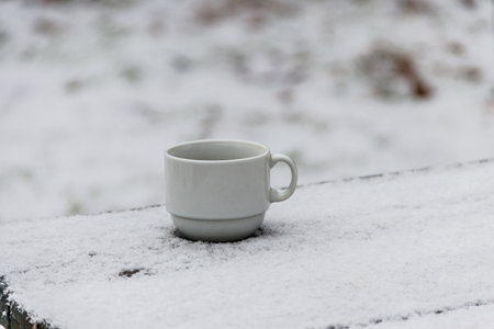 Cup of coffee on a snow covered table at winterの写真素材