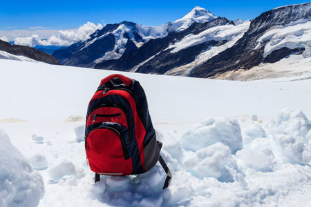 Tourist backpack on a snow on background of mountains in Swiss Alps. travel outdoor conceptの写真素材