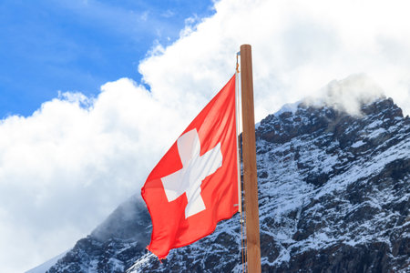 Red Swiss flag over the Swiss Alps backgroundの写真素材