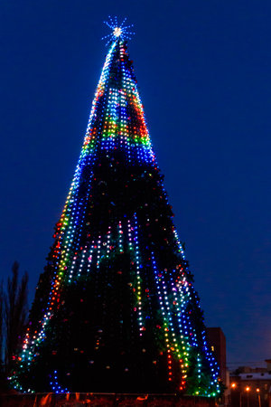 Decorated Christmas tree with multi-colored lights at nightの写真素材