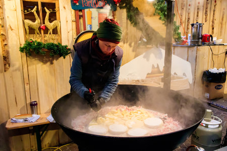 Montreux, Switzerland â November 27, 2022: Cooking of tartiflette, a traditional French dish of scalloped potatoes, bacon and cheese, in big cauldron during the Christmas market in Montreux, Switzerlandのeditorial素材