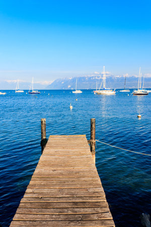 Wooden pier overlooking the Alps and Lake Geneva in Switzerlandの写真素材