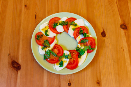 Italian caprese salad with tomatoes, mozzarella cheese and basil on a wooden table. Top viewの写真素材