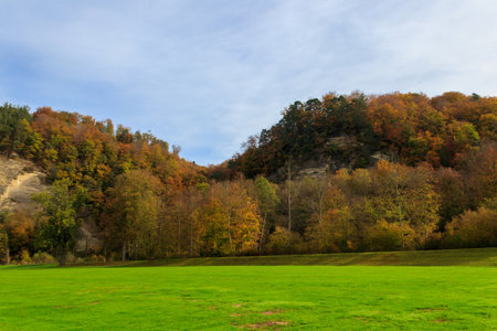 Beautiful colorful autumn landscape of the hills with trees, rocks and green lawns in countrysideの写真素材