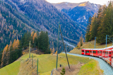 Red passenger train on Rhaetian railway in Canton Graubunden, Switzerland at autumnの写真素材