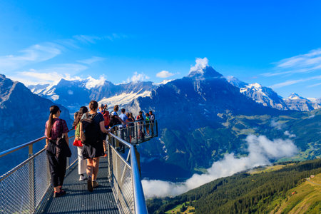 Grindelwald,  Switzerland - August 6, 2022: Tourists take photos on the First Cliff Walk, a popular viewing platform on the First mountain in Grindelwald, which offers with stunning Alpine viewsのeditorial素材
