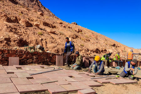 South Sinai, Egypt - January 29, 2022: Workers lays paving slabs at construction site in desert in Sinai peninsula, Egyptのeditorial素材
