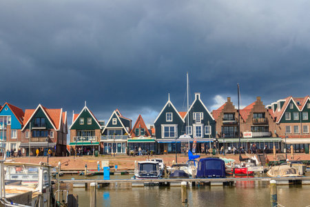 Volendam, Netherlands - April 24, 2024: View of Volendam - small town fishing village in North Holland near Amsterdam with traditional houses with red regular roofs at waterfront with docks by seaのeditorial素材