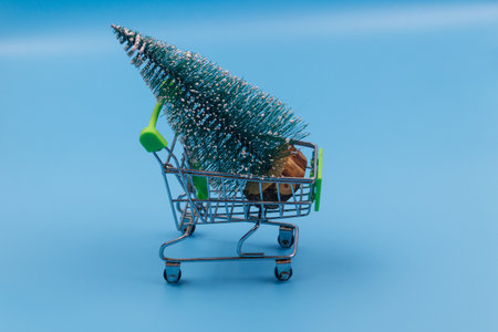 Shopping cart with Christmas tree on pastel blue background. Christmas shopping conceptの写真素材