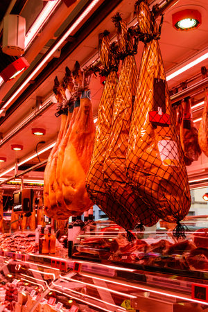 Jamon serrano ham legs hanging in a traditional spanish marketの写真素材