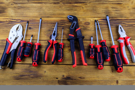 Set of different pliers and screwdrivers on wooden background. Top viewの写真素材