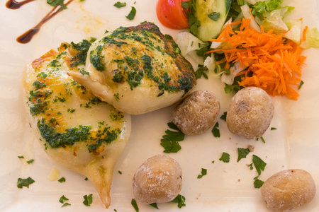 Grilled squid with canarian potatoes and vegetable salad on a plate