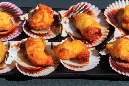 Deep-fried battered scallops in its shell on a tableの写真素材