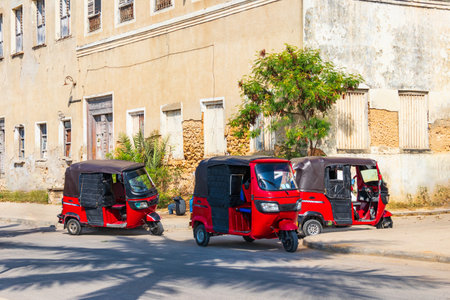 Tuk-tuks, parked by the roadside, in the historic Stone Town of Zanzibar, Tanzaniaの写真素材