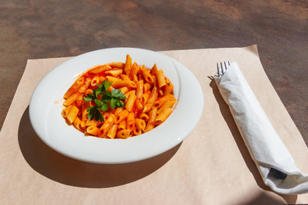 Penne arrabiata - traditional italian pasta with spicy sauce on a tableの写真素材