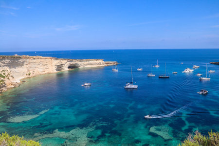 Beautiful coastal view of Delimara peninsula with rocks and turquoise sea with yachts on Maltaの写真素材