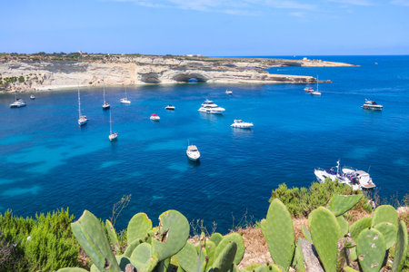Beautiful coastal view of Delimara peninsula with rocks and turquoise sea with yachts on Maltaの写真素材