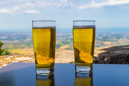 Two glasses of beer on a table with a view of San Marinoの写真素材