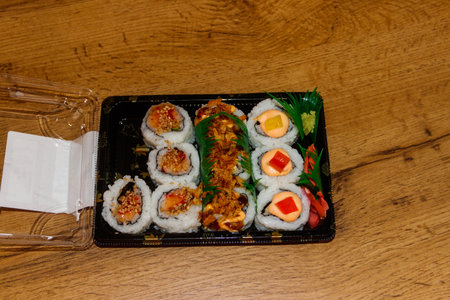 Set of sushi rolls in plastic box on wooden table. Sushi for take away or delivery of sushi in plastic containerの写真素材