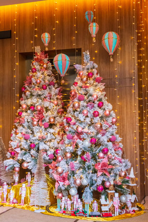 Decorated Christmas trees with pink ornaments in a festive storefront displayの写真素材