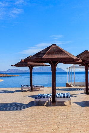 Sun umbrellas and chaise lounges on tropical beach. Concept of rest, relaxation, holidays, resortの写真素材