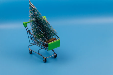 Shopping cart with Christmas tree on pastel blue background. Christmas shopping conceptの写真素材