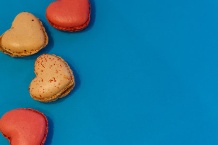Sweet heart shaped macaroons on blue background. Top view, copy space. Valentine Day conceptの写真素材