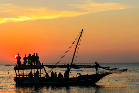 Zanzibar, Tanzania - September 16, 2021: Traditional wooden dhow boat with tourists sailing in the...