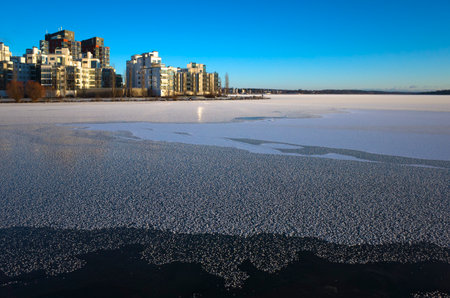 Winter day in Scandinavia, Frost covered ice of frozen lake Malaren, view of Lillaudden residential area on lake front, Vasteras, Swedenの写真素材