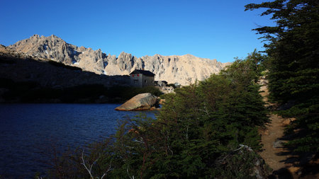 Hiking trail in bushes, stone house, mountain lake, lifeless rocky mountain peaks, Toncek lagoon and Refugio Frey in Cerro Catedral in Nahuel Huapi National Park, Nature of Patagonia, Argentinaの写真素材