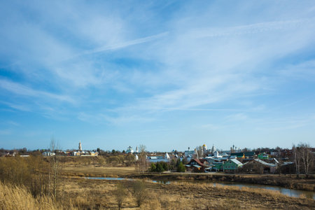 Panorama of Suzdal in spring middle april, Dry grass, small river Kamenka, russian traditional houses and churches on horizon in sunny day, Russiaの写真素材