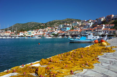 Pythagorion, Samos island, Greece - 13 May, 2018: Traditional colorful fishing net in foreground with boats on water and town houses on hillのeditorial素材