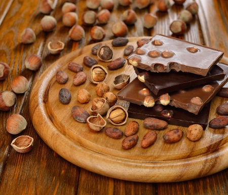 Chocolate with hazelnuts and cocoa beans on a brown tableの写真素材