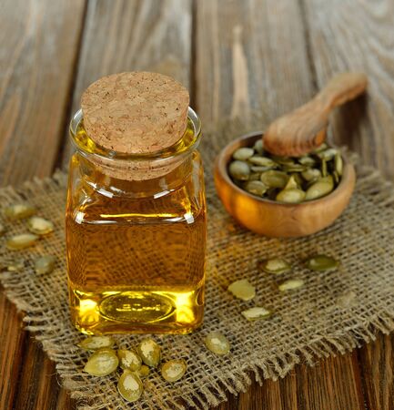 Pumpkin seed oil in a glass bottle on a brown tableの写真素材