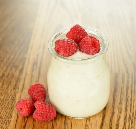 Yogurt with raspberries on a brown tableの写真素材