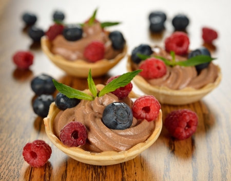Chocolate dessert with raspberries and blueberries on a brown tableの写真素材