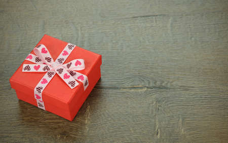red box decorated with ribbon on brown background